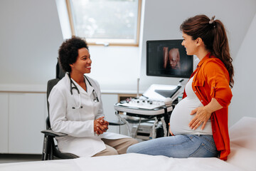 Cheerful doctor with pregnant patient.