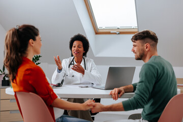 Cheerful doctor with pregnant couple.