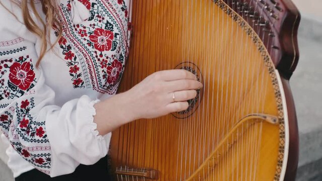 Ukrainian woman folk artist in embroidery shirt playing the bandura