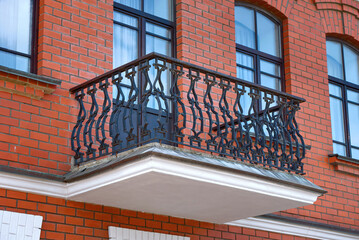 Balcony with wrought iron railings. Architectural elements of red brick building with balcony. Balcony with forging railing. Architectural detail..