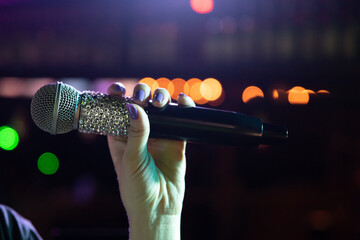 Radio microphone in woman hand in the karaoke night club.