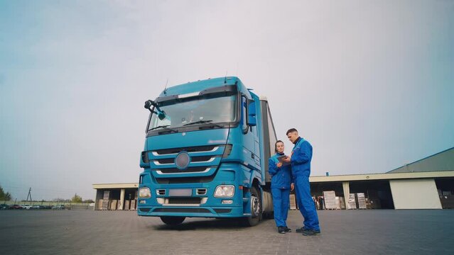 Truck drivers check cargo documents near the truck. Route discussion. Partners.
