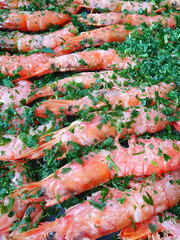 Whole baked red prawns on a baking sheet with herbs. View from above