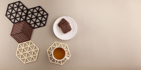 a white cup of green tea on a silicone stand for hot. Nearby there are silicone coasters for hot in different colors. Banner with space for text