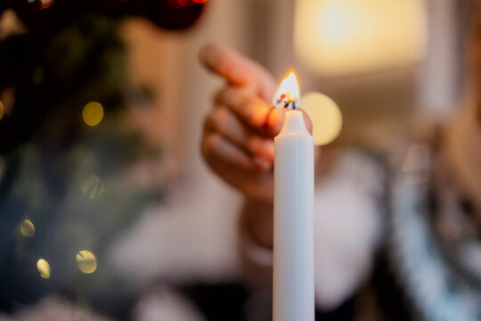 Close-up shot of a woman's hand lighting a candle using matches. Christmas holiday