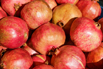 Juicy ripe pomegranate fruits on the market counter for juice. Pomegranate harvest on agricultural farm, vitamins, fruits, tropics concept.