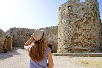 Holidays in Rhodes, Greece. Back view of traveler girl visiting Rhodes fortifications. Young female...