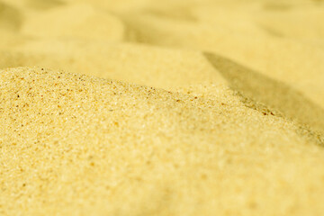 Close-up of yellow sand on the beach. Small grains of sand on a clean beach. Toned photo with low depth of field.