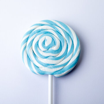 Blue striped candy on a stick, white background. Lollipop