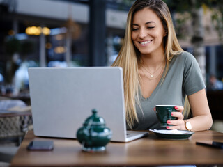 A woman sits in a coffee shop and follows online course.