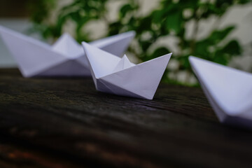 Origami, white paper boat isolated on a wooden floor.  Paper boats mean walking.  feeling of freedom  leadership