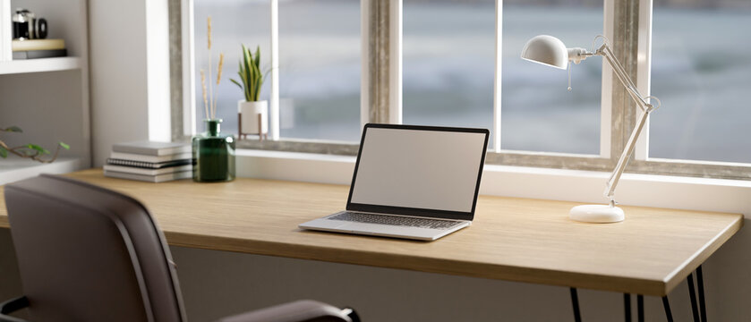Minimal Scandinavian home workspace with laptop mockup on wood table against the window