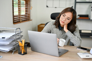 Tired and bored Asian businesswoman looking at her laptop, pondering and pensive thinking