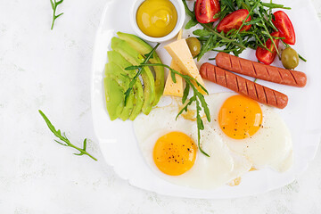 English breakfast - fried eggs, sausages, tomatoes, avocado, cheese and olives. American food. Top view, overhead, copy space