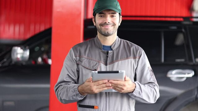 Portrait happy automobile mechanic man standing looking at the camera and smiling. diagnostic and repairing vehicles at garage automotive, Car care check and fixed and services insurance concept.