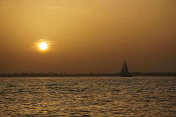 Barca a vela con il sole che tramonta alle sue spalle