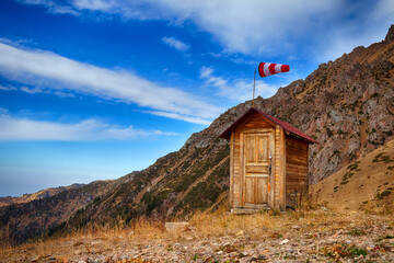 House in the mountains with a weather vane to indicate the direction of the wind - 544307176