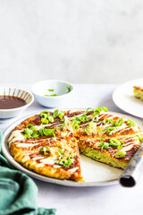 Okonomiyaki or the Japanese savory pancake filled with cabbage and served with spring onion and katsuboshi