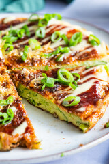 Okonomiyaki or the Japanese savory pancake filled with cabbage and served with spring onion and katsuboshi