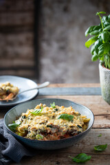 Delicious creamy zucchini pasta with cheese and basil plant in the background on a table