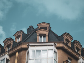 Facade with windows on top of a building with the sky and clouds in the background.