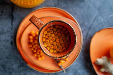 Sea buckthorn tea, top view. Still life cup with tea, berries and lemons. Orange sea buckthorn drink, juice. Autumn mood.