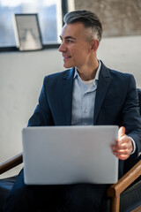 Elegant good-looking man in a suit working on a laptop