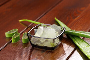 Aloe vera leaves with cut and peeled slices on a wooden background. Angle view. Selective focus.