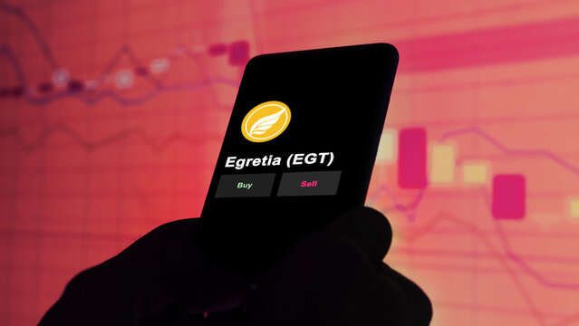 November 3th 2022, Berlin. An investor's analyzing the Egretia token 'EGT' coin on screen. A phone shows the crypto's prices to invest