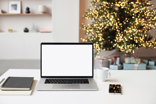 Beautiful Christmas workplace, laptop computer with blank white mockup screen. Online shopping during winter holiday, ordering xmas gifts concept. Website template
