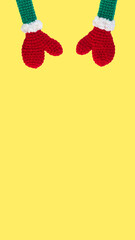 two knitted toys red mittens on green sleeves with white cuffs top left diagonally on yellow backgtound, isolate, vertical, 16:9