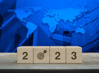 2023 letter with goal icon on wood block cubes on wooden table over world map, modern office city...
