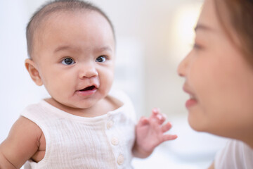 Closeup Mom happy joyful teasing asian infant baby new born sitting on bed and kiss her