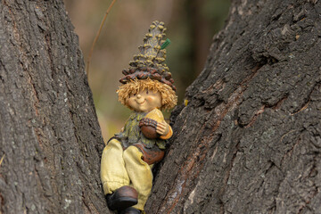 A little gnome, dwarf sits on the tree in an autumn forest, park.