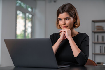 Pensive attractive businesswoman working on laptop holding hands in lock