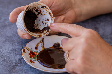 Female fortune teller making predictions on coffee grounds at the table.