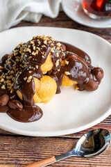 Profiterole dessert on wood background. Traditional french cuisine delicacies. Profiterole dessert topped with chocolate and hazelnut pieces. close up