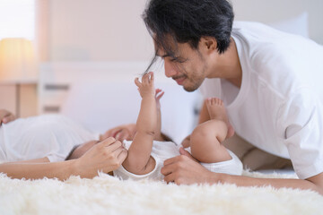 Mom and father happy joyful teasing asian infant baby new born have fun looking to parent face