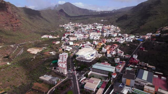 Aerial tilt up reveal of a town in a green mountain landscape environment
