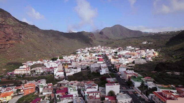 Aerial rising panoramic view of a town in Tenerife, green hill landscape