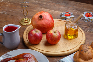 Honey, challah apples pomegranates and dates wine and candles on the table in Rosh Hashanah.