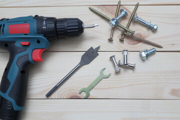 set of tools on wooden table, a electric screwdriver with a set of drill bits and screws with bolts. work tool on wooden background. Hand tool closeup