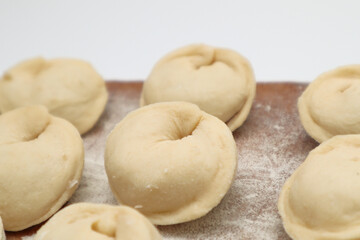 Preparation of dumplings Pelmeni. There are group of dumplings on a wooden board . Selective focus