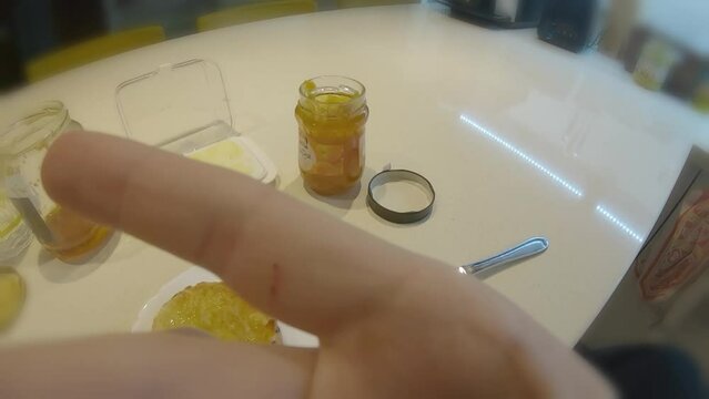 POV first person eating bread with jam for breakfast in modern kitchen