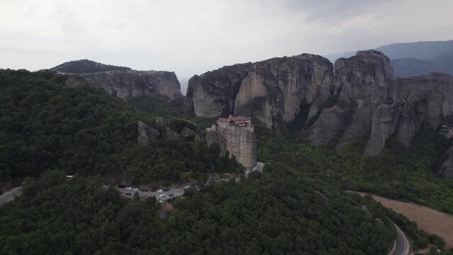 Circling aerial view of Monastery of Rousanou on top of a cliff in Meteora Greece, mountain landscape