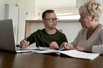 Caucasian man with down syndrome learning with his mum at home