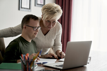 Caucasian man with down syndrome learning with his mum at home