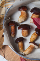 Vintage baking sheet with Imleria Badia or Boletus badius mushrooms commonly known as the bay bolete on wooden cutting board..