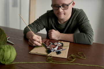 Adult caucasian man with down syndrome making a craft
