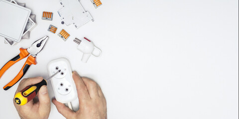 top view of electrician repairing electrical socket on desk. banner with copy space.